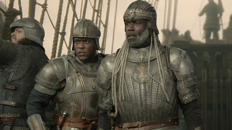 Abubakar Salim as Alyn of Hull standing on the deck of a ship next to Steve Toussaint as Corlys Velaryon in full armor in House of the Dragon