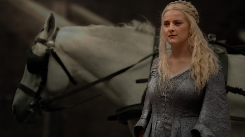 Phia Saban as Helaena Targaryen standing in front of a white horse in House of the Dragon