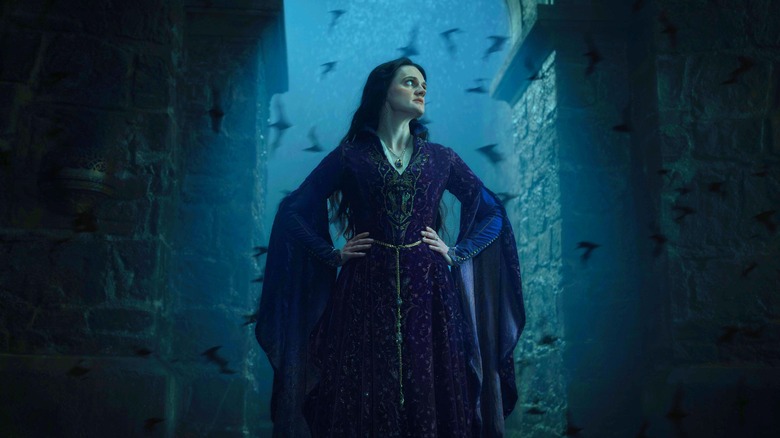 Gayle Rankin as Alys Rivers standing by a doorway with several bats flying behind her in House of the Dragon