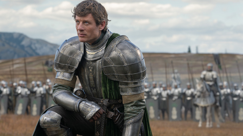 James Norton as Ormund Hightower wearing a suit of armor on a battlefield and kneeling in front of an army in House of the Dragon