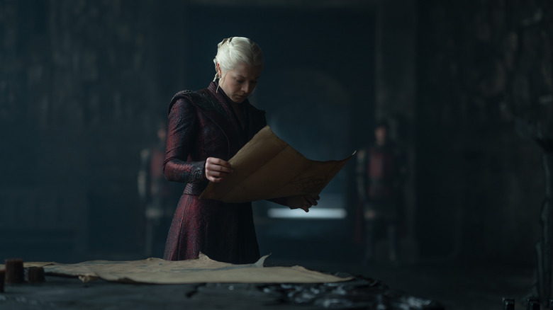 Emma D'Arcy as Rhaenyra Targaryen dressed in red and holding up a map in House of the Dragon