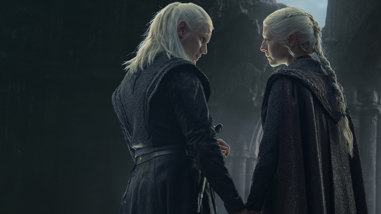 Matt Smith as Daemon Targaryen holding hands with Emma D'Arcy as Rhaenyra Targaryen in a castle in House of the Dragon