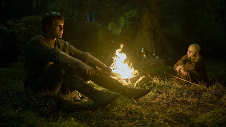 Peter Claffey as Ser Duncan the Tall sitting by a campfire opposite from Dexter Sol Ansell as Egg in A Knight of the Seven Kingdoms