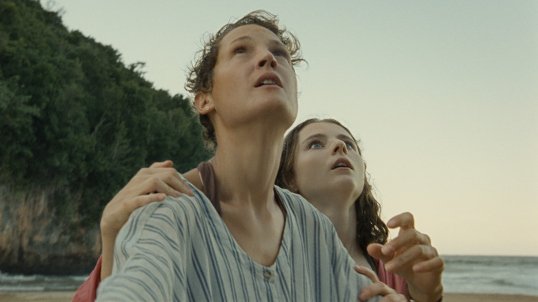 Vicky Krieps as Prisca and Thomasin McKenzie as Maddox looking up at the sky in Old