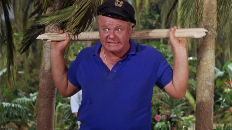 The Skipper, holding a beam across his shoulders. He is wincing.