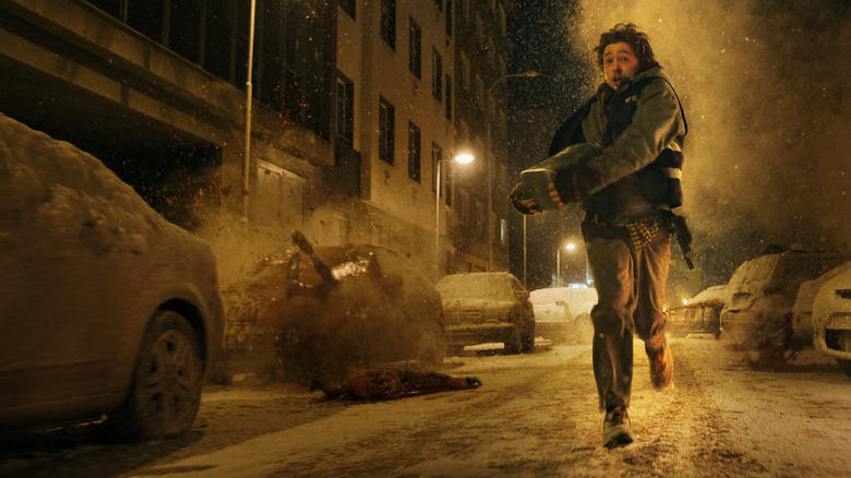 Austin Abrams as Bryan running through a snowy street next to several abandoned cars in Resident Evil (2026)