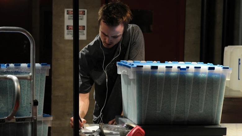 Aaron Paul as Jesse filling out forms while he weighs a crate of blue meth on Breaking Bad