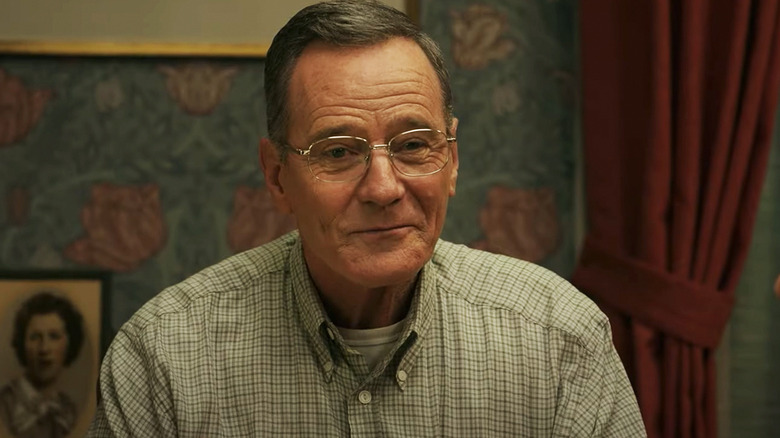 Bryan Cranston's Jerry Selbee smiles as he sits at a dining room table in Jerry and Marge Go Large