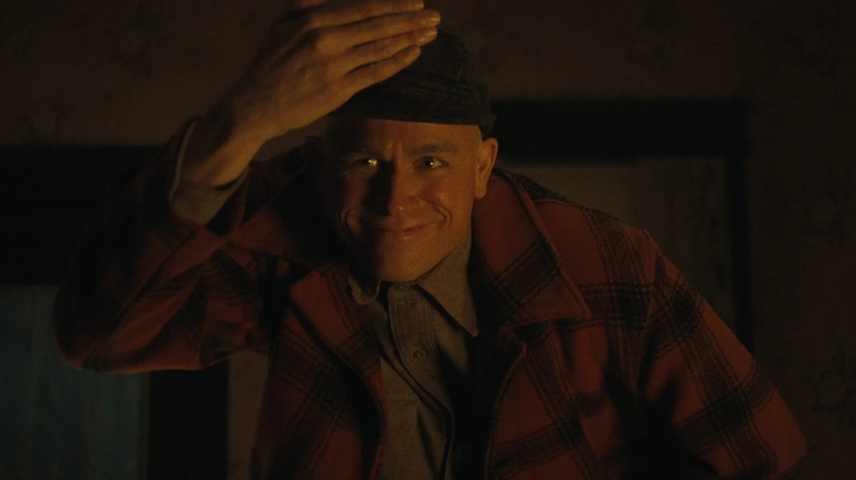 Charlie Hunnam as Ed Gein standing in the shadows with a menacing look in Monster: The Ed Gein Story