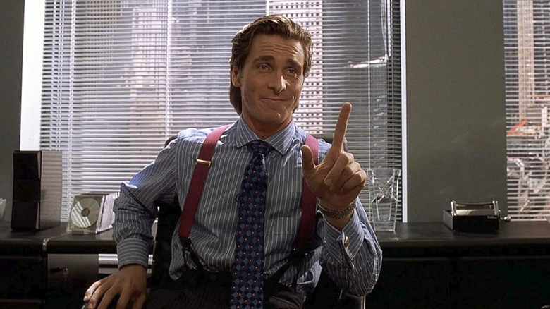 Christian Bale as Patrick Bateman holding his fingers up in American Psycho