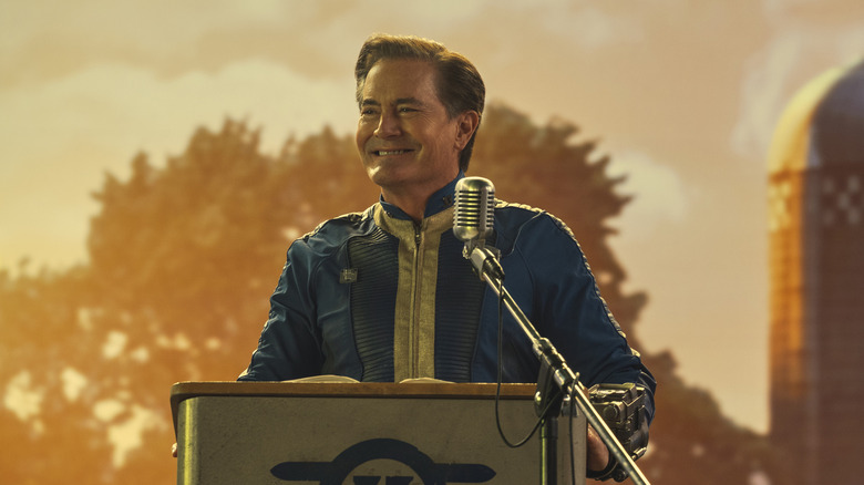 Hanks smiling at a podium with a microphone on Fallout