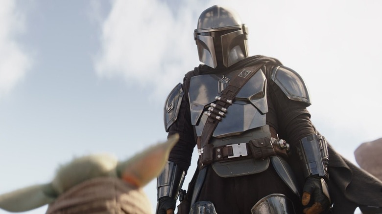 Mando looking down at Grogu in The Mandalorian Season 3