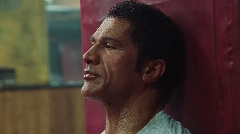 Dwayne Johnson as Mark Kerr slumped against a post in The Smashing Machine