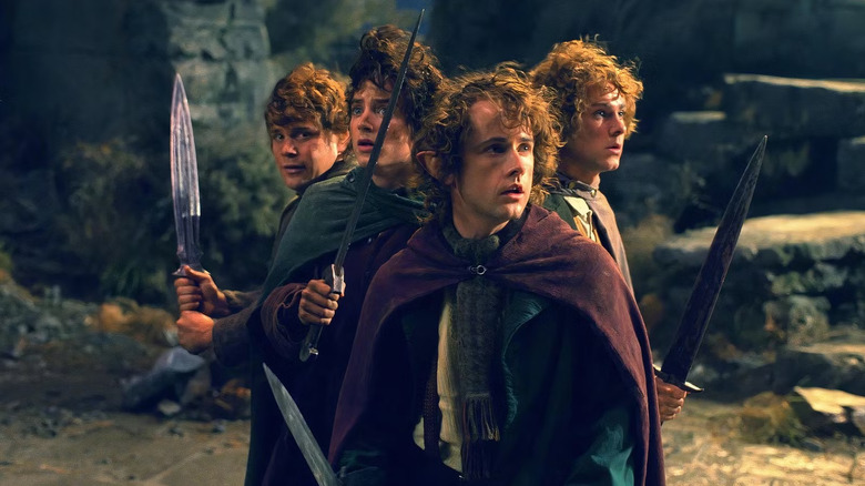 Sam, Frodo, Pippin, and Merry on the hilltop holding swords in The Lord of the Rings: The Fellowship of the Ring
