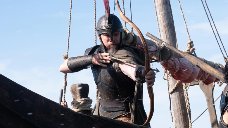 Matt Damon as Odysseus preparing to fire an arrow aboard a boat in The Odyssey (2026)