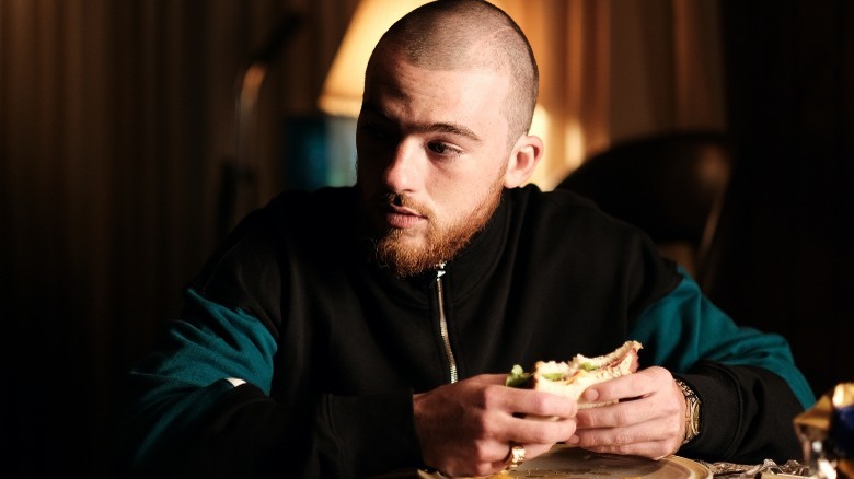 Fezco eats a sandwich