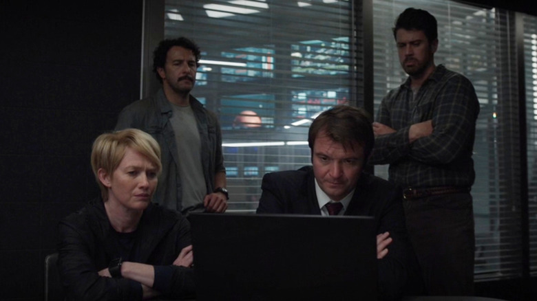 Costa Ronin as Governor Leonid Polivanov sitting in front of a laptop next to Mireille Enos as Celia Boyd, Salvador Chacon as Gerardo Ortiz-Niño, and Toby Kebbell as Miles Dale in For All Mankind