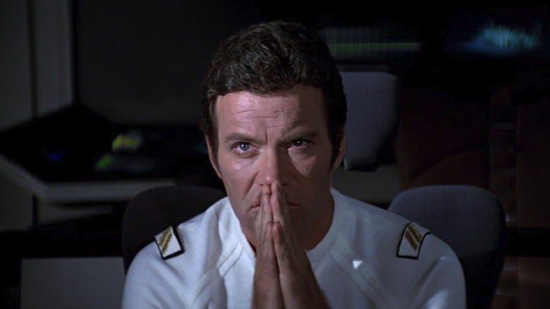 William Shatner as Kirk sitting on the bridge with his hands folded in front of his mouth in a praying pose in Star Trek: The Motion Picture