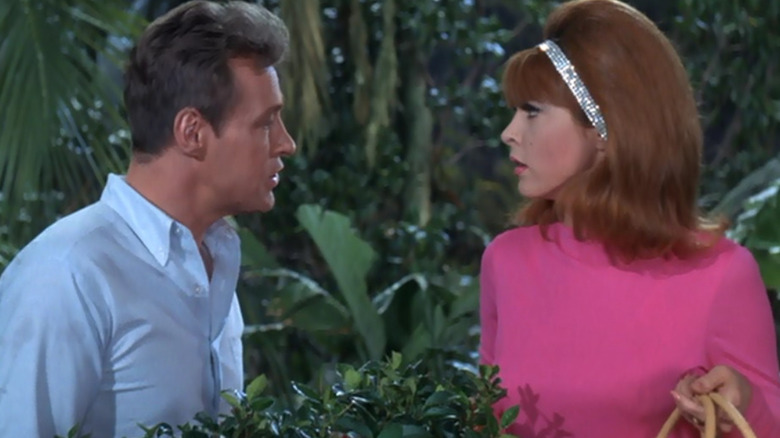The Professor and Ginger standing behind a bush and looking at one another on Gilligan's Island