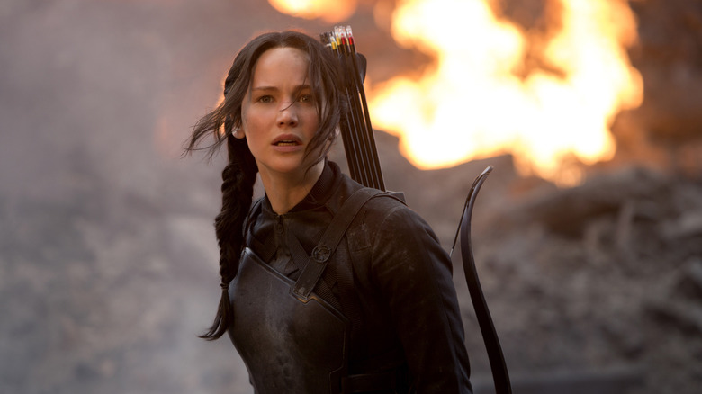 Jennifer Lawrence as Katniss Everdeen looking up in distress with flames behind her in The Hunger Games: Mockingjay - Part 1
