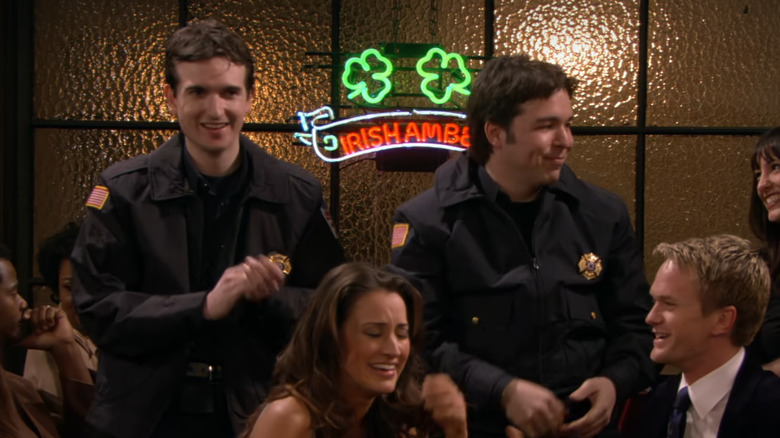 How I Met Your Mother, two fake paramedics (played by Bays and Thomas), behind Barney and a girl he's picking up