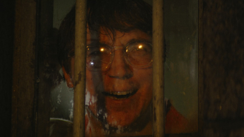 Paul Dano as the Riddler smiling behind bars in The Batman