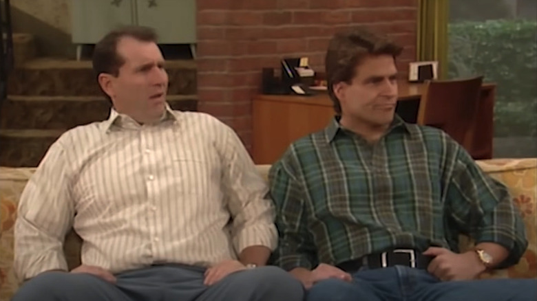 Ed O'Neill's Al Bundy sits on a couch next to Ted McGinley's Jefferson D'Arcy in Married... with Children