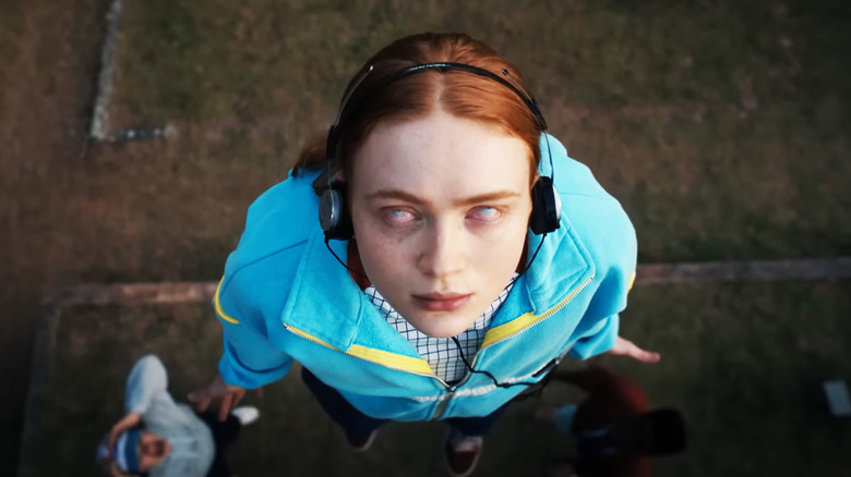 Sadie Sink's Max Mayfield levitates off the ground while wearing headphones in Stranger Things