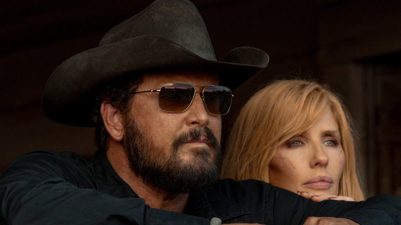 Cole Hauser's Rip Wheeler looks off into the distance wearing shades next to Kelly Reilly's Beth Dutton in Dutton Ranch