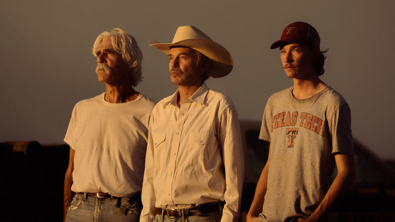 Sam Elliott's T.L. Norris stands alongside Billy Bob Thornton's Tommy Norris and Jacob Lofland's Cooper Norris against a clear sky in Landman