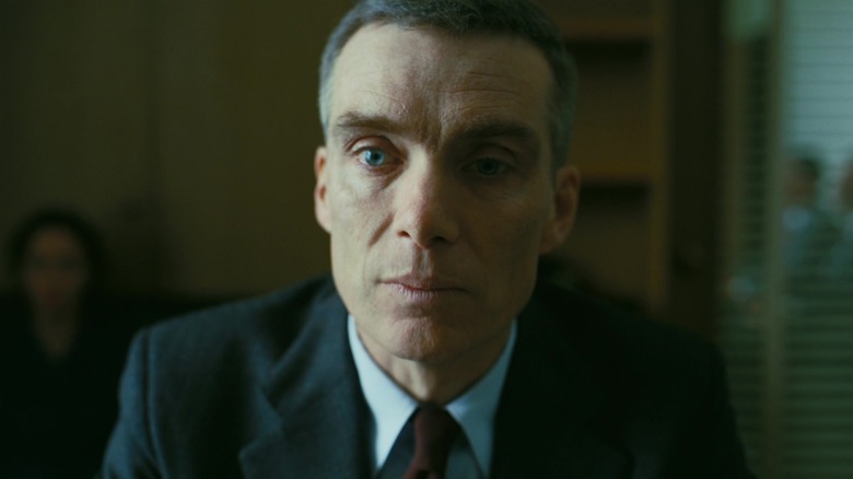Robert Oppenheimer sitting down and looking stressed out in Oppenheimer