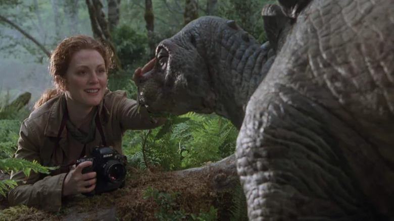 Sarah Harding smiles as she pets a dinosaur in The Lost World: Jurassic Park