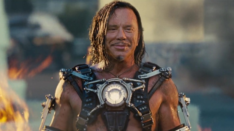 Whiplash grinning on a racetrack, surrounded by flames, in Iron Man 2