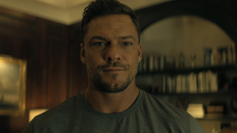 Alan Ritchson as Jack Reacher stands in Beck's mansion in Reacher