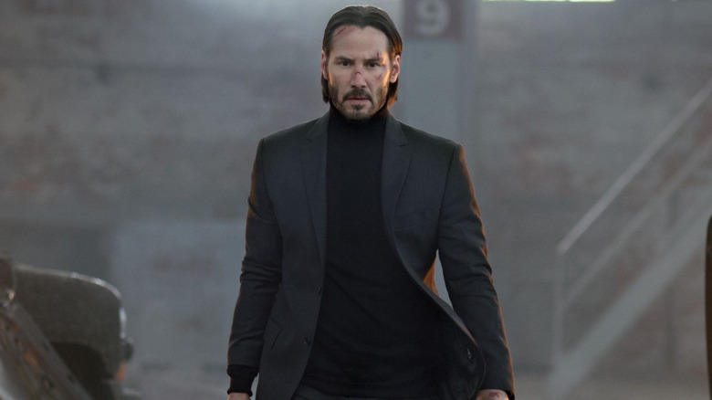 Keanu Reeves in the role of John Wake, who walks next to the burning cars in the warehouse in John Wake