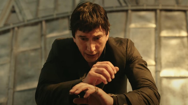 Adam Driver as Cesar leaning over the side of a building with a look of fear on his face in Megalopolis