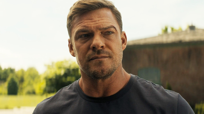 Alan Ritchson as Jack Reacher is held outside Reacher