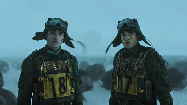 Robert Pattinson's Mickey 17 and Mickey 18 standing together in the snow in Mickey 17