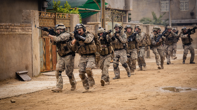 Charles Melton as Jake leading a squad of heavily-armed soldiers through the streets of Iraq in Warfare