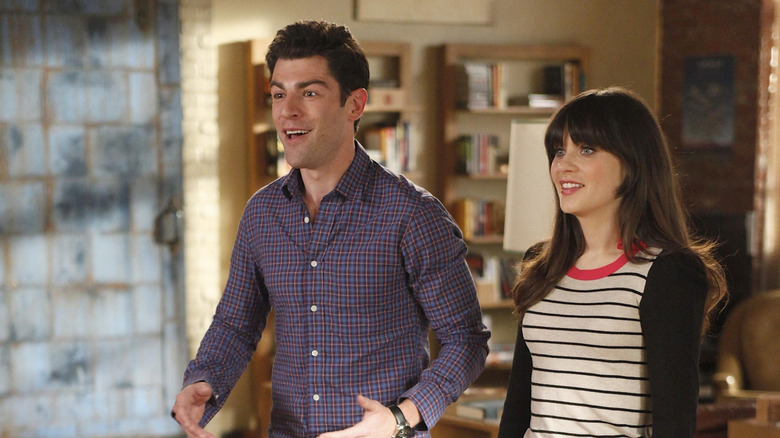 Jess and Schmidt standing in the living room smiling in the New Girl episode Control