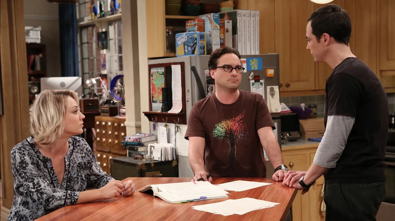 Kaley Cuoco as Penny, Johnny Galecki as Leonard, and Jim Parsons as Sheldon gather around a table in The Big Bang Theory