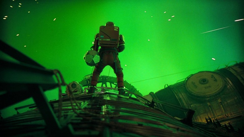 Ryan Gosling's Ryland Grace stands on top of his ship in front of a green glow in Project Hail Mary