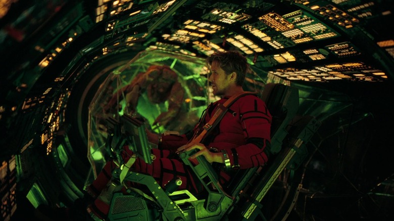 Ryan Gosling's Ryland Grace sits at a control array while Rocky waits in the background in Project Hail Mary