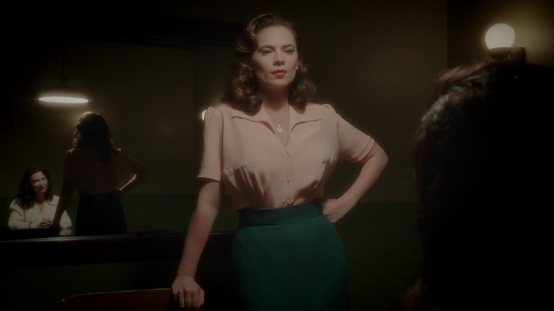 Agent Carter in a pink blouse and stands in the interrogation room in Carter agent