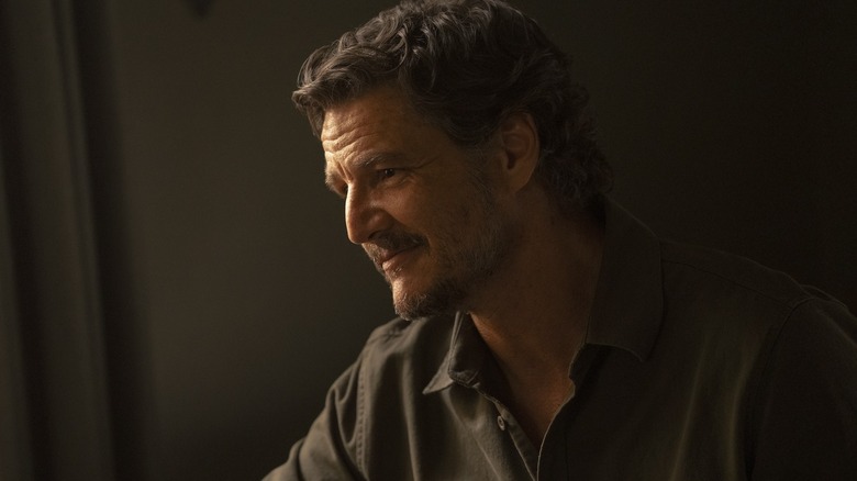 Joel in half-light smiling in a black shirt on The Last of Us