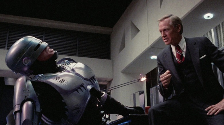 RoboCop leaning back in Dick Jones' office in RoboCop (1987)