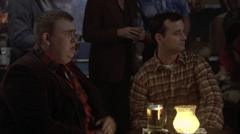 Bill Murray as John Winger shares a bar table with John Candy with Dewey 