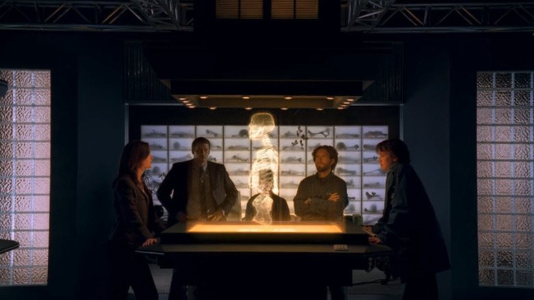 The Bones cast gather round a holographic projection in Bones