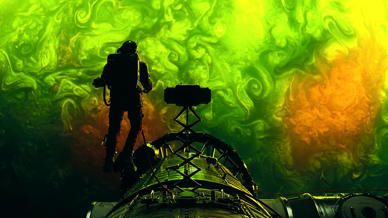 Ryan Gosling as Ryland Grace stepping outside his spaceship with a tether in front of a glowing green planet in Project Hail Mary