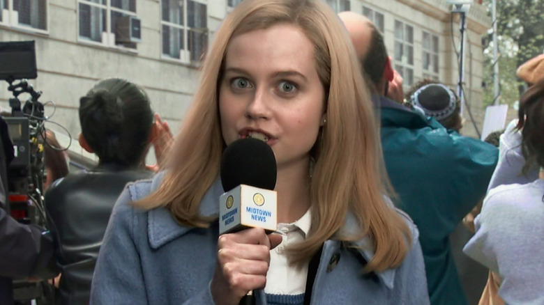 Angourie Rice as Betty Brant with a Midtown News microphone in front of a crowd in Spider-Man: No Way Home